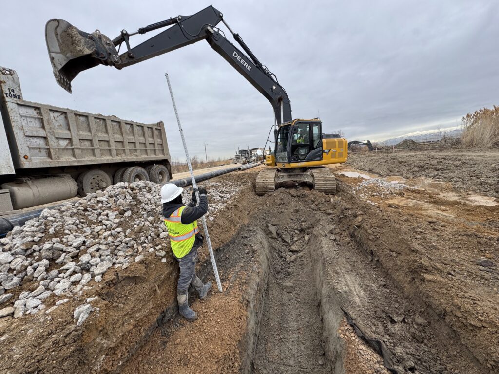 Road infrastructure under construction with excavators and crew in Utah.